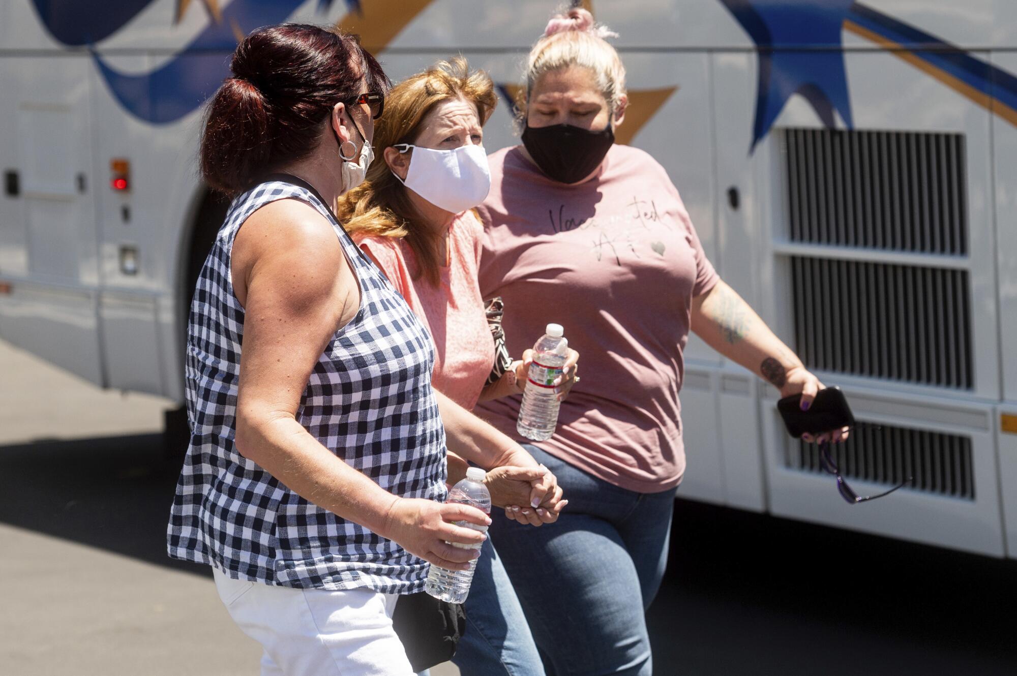 Three women in face masks walk together.
