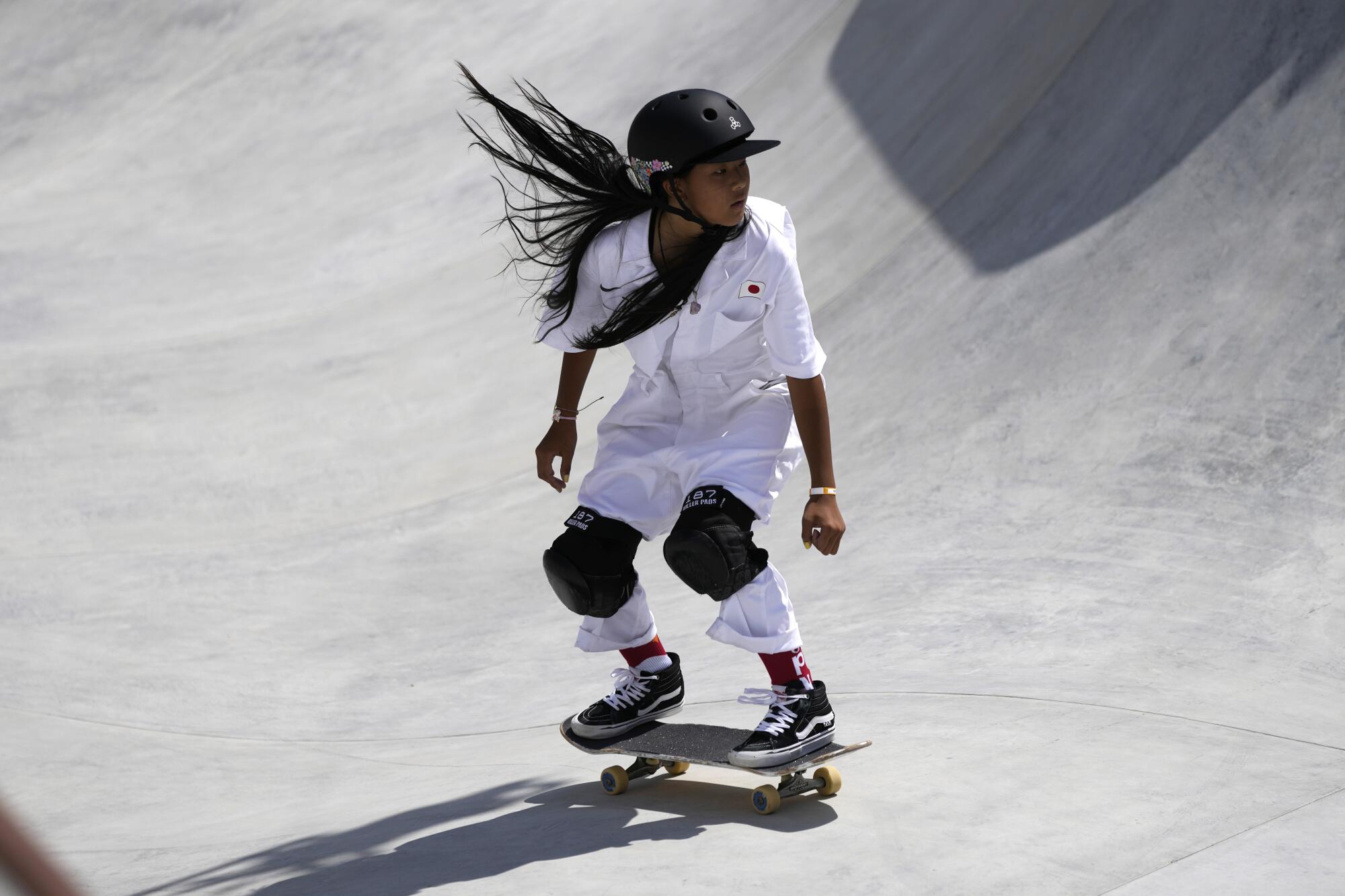 A skateboard crouches on her board.