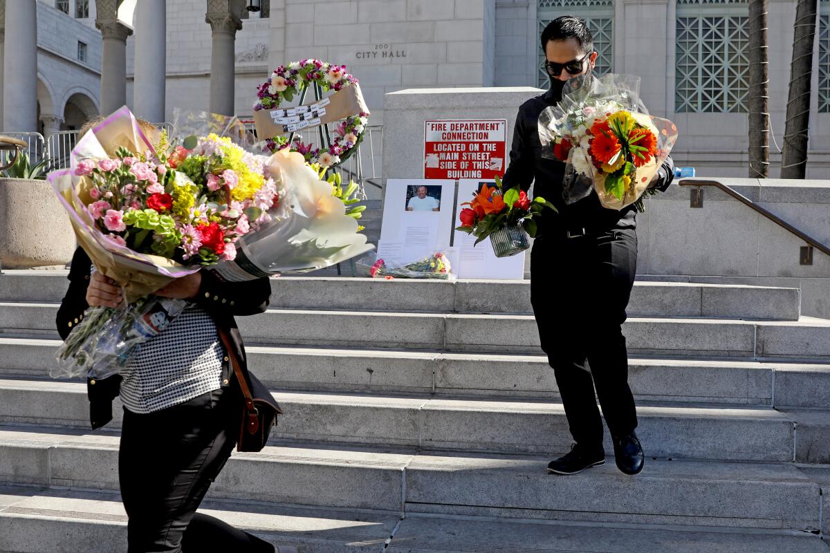 Mourners hold flowers on the steps of City Hall.