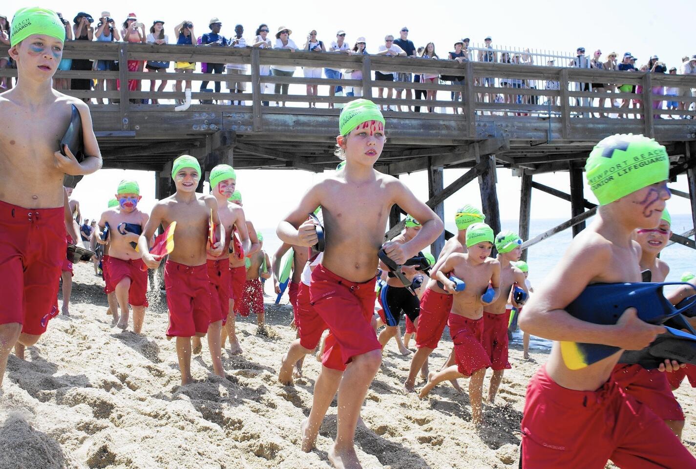 The boys' group D start their run during the annual monster mile event for the Newport Beach junior lifeguards at the Balboa Pier on Thursday, July 30.