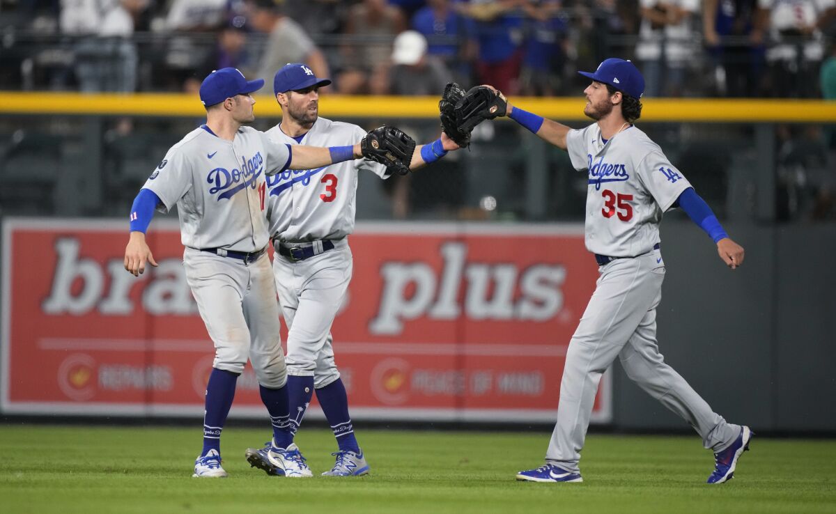 Los Angeles Dodgers left fielder AJ Pollock, center fielder Chris Taylor and right fielder Cody Bellinger, from let, celebrate after the team's baseball game against the Colorado Rockies on Saturday, July 17, 2021, in Denver. The Dodgers won 9-2. (AP Photo/David Zalubowski)