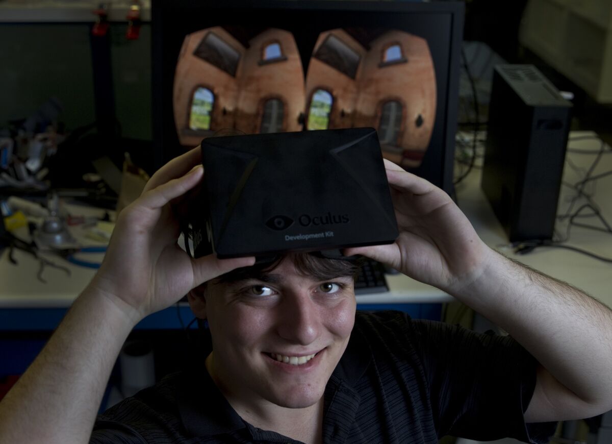 Palmer Luckey, seen in 2013, holds the virtual reality machine he created for Oculus called Rift.