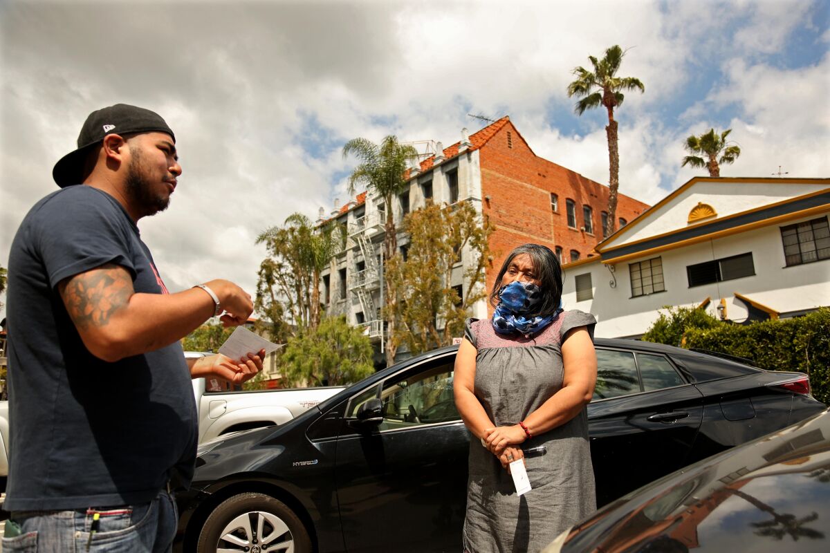 Odilia Romero talks with Francisco Vasquez Gonzalez, 31, from Oaxaca, Mexico, after giving him a relief check. Vasquez lost his jobs as a cook at two Century City restaurants.