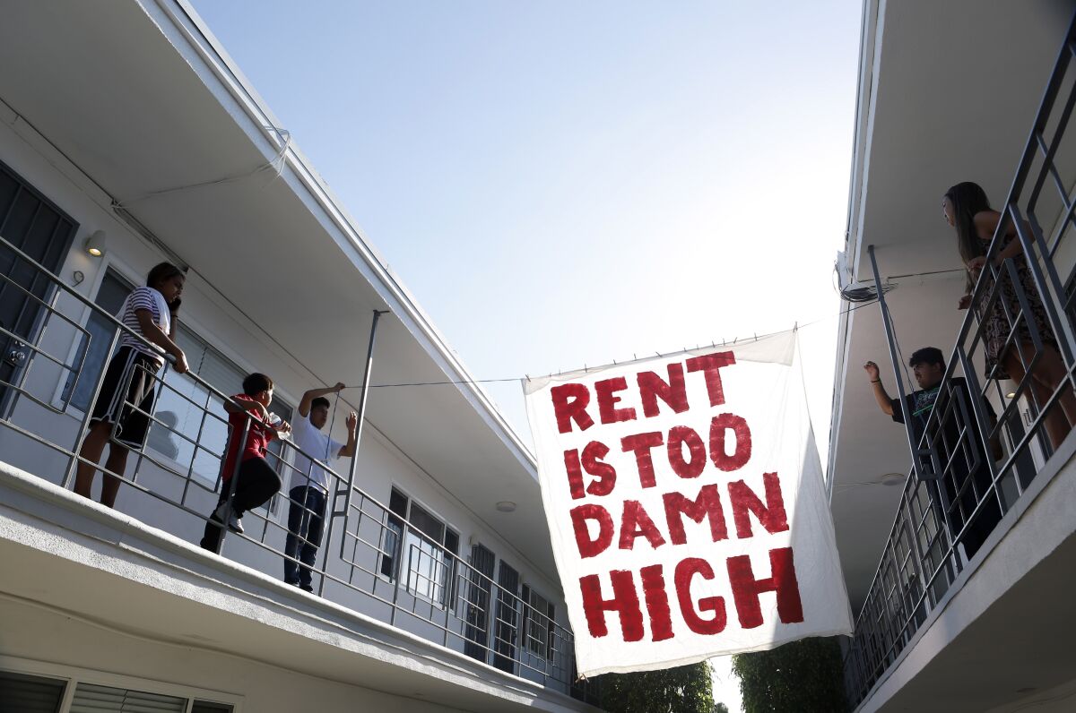 Organizers with the advocacy group Housing Long Beach hang a sign in the courtyard of a Cedar Avenue apartment complex.