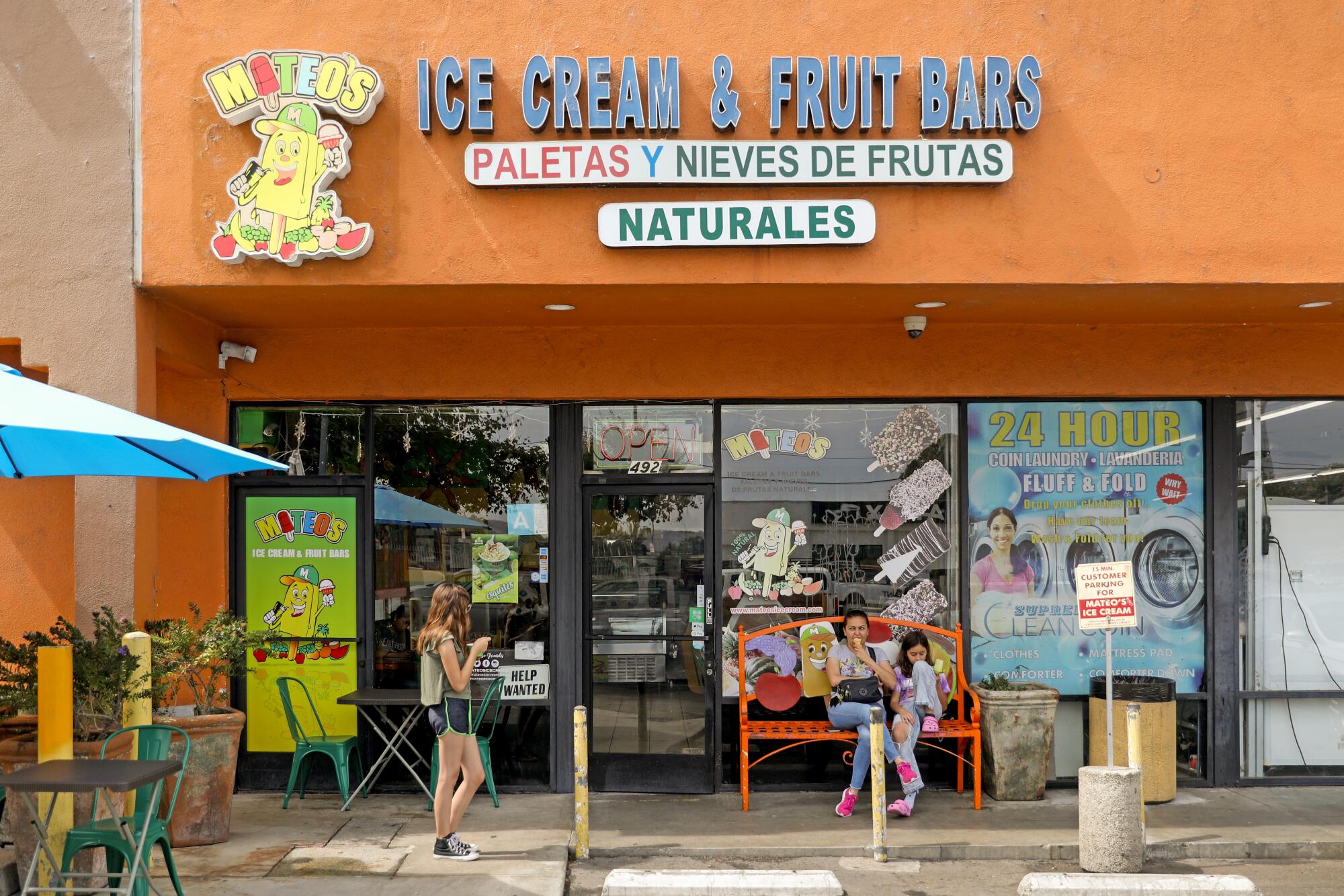 A mother and daughter enjoy paletas outside a shop