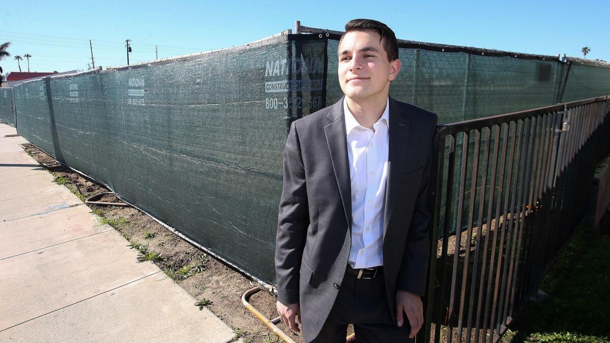 Dilan Oezkan stands next to a fence surrounding the site of the now-razed Costa Mesa Motor Inn, which provided inexpensive rooms to his family when he was a boy. Oezkan grew up homeless, moving from motel to motel with his family as a child.