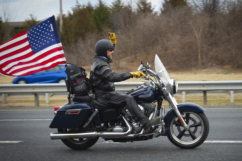 A supporter rides a motorcycle near the New Design Road bridge over I-270 in Frederick County as the “People’s Convoy” passed through the county as they made their way from Hagerstown to Washington, Sunday, March 6, 2022. (Bill Green/The Frederick News-Post via AP)