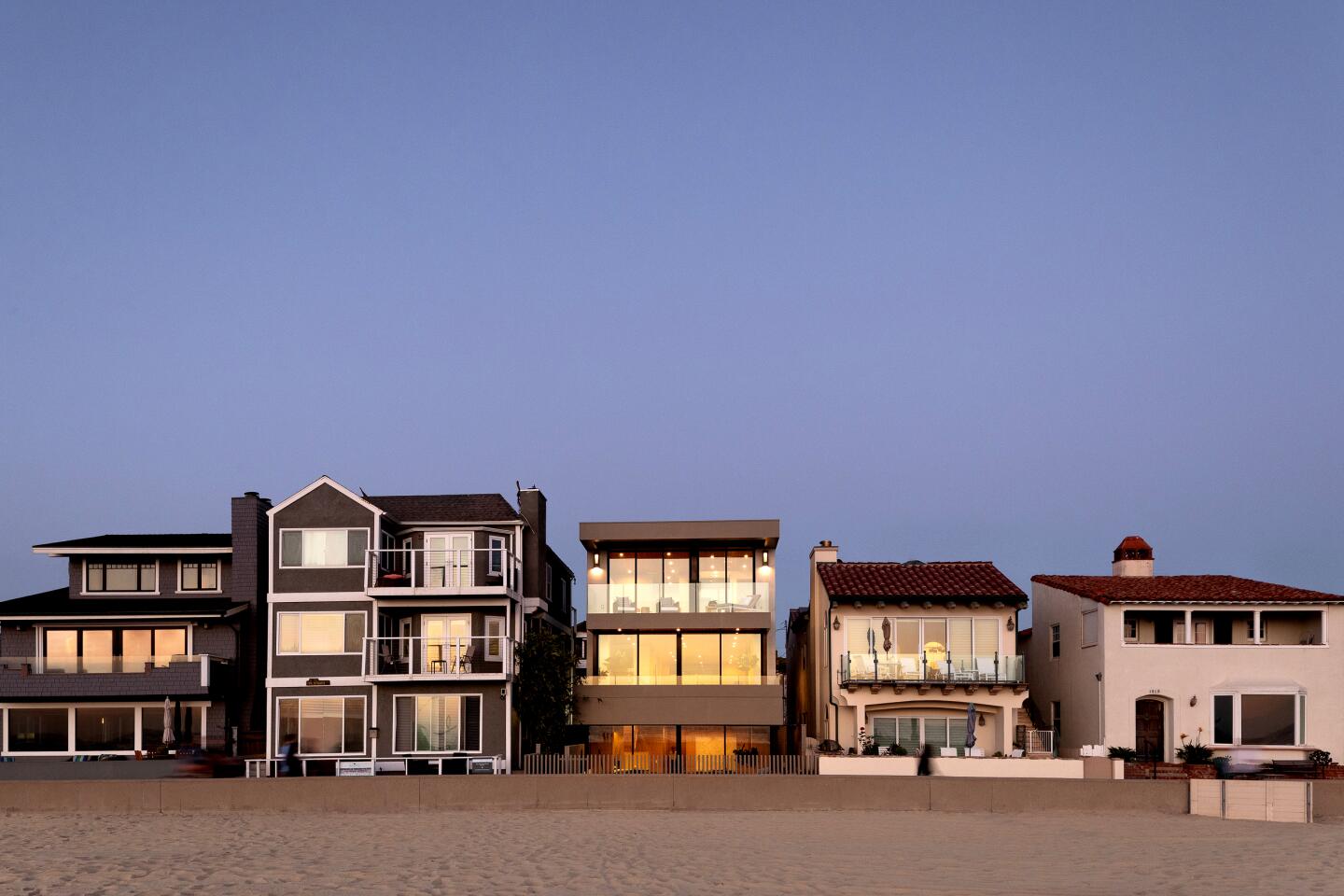 The three-story home takes advantage of the coastal setting with an indoor-outdoor living room and sunken courtyard next to the sand. Built in 2020, the modern beach house holds stylish living spaces with warm woods, stone accents and glass walls.