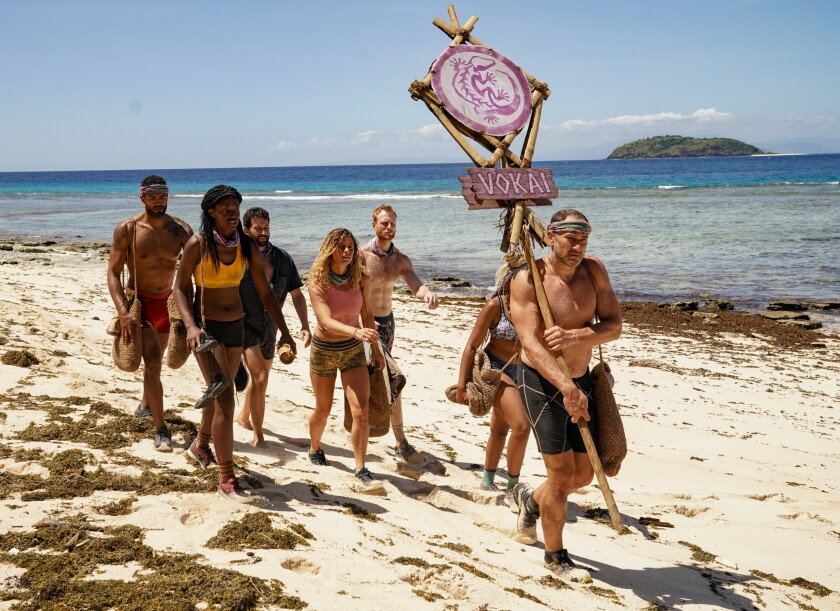 "Survivor: Island of Idols" contestants walk across a sandy beach.