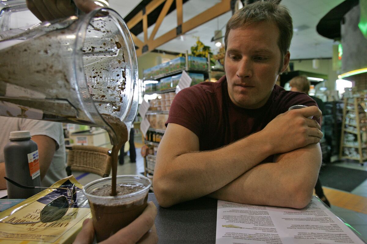 Matt Neely watches as his ice blended maca drink is poured at the tonic bar at Erewhon Natural Foods Market in Los Angeles