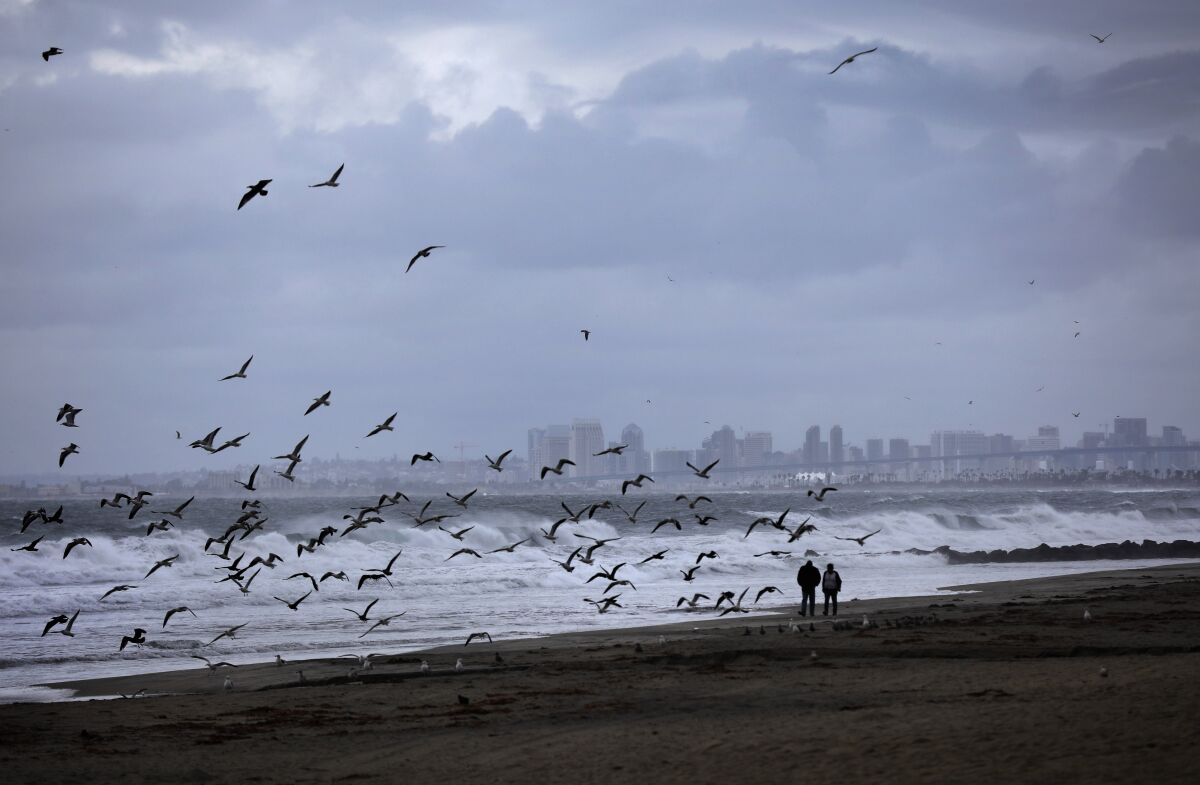 People walk along the coast in Imperial Beach as the first storm of the season moved through the area on Wednesday. Forecasters expect another big storm the middle of next week.
