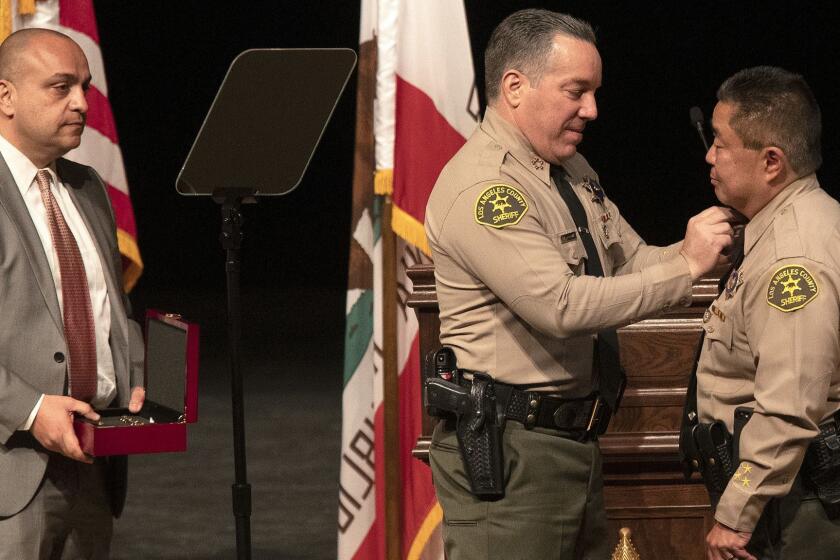 MONTEREY PARK, CA-DECEMBER 3, 2018: left to right-Los Angeles Count Sheriff's Deputy Caren Carl Mandoyan looks on as Alex Villanueva, the new Los Angeles County Sheriff, places a pin on the collar of Maria Gutierrez during a ceremony at East Los Angeles College in Monterey Park on December 3, 2018. Villanueva was sworn in as the Sheriff of Los Angles County. (Mel Melcon/Los Angeles Times)