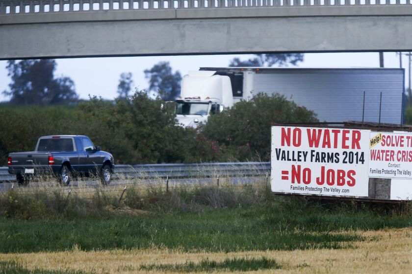 Signs along Highway 99 near Chowchilla connect water cutbacks prompted by the drought to agricultural employment.