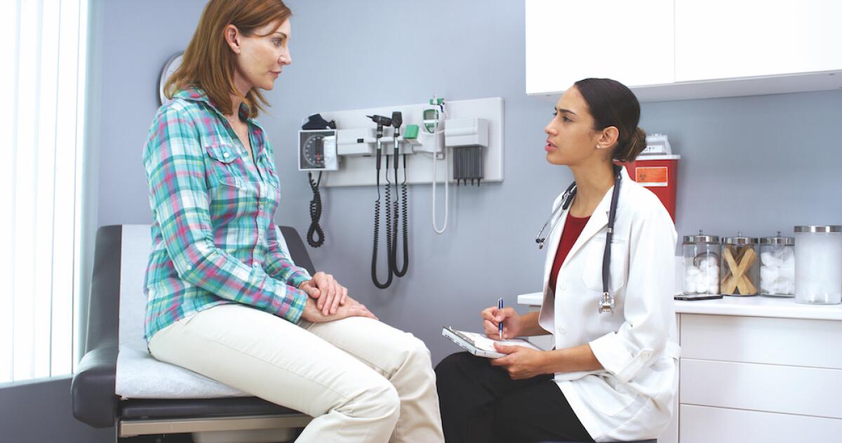 A woman consults with a female doctor in a medical exam room.