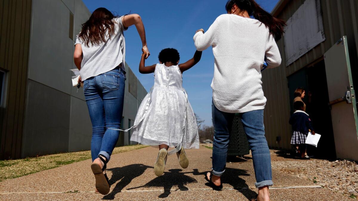 Pity Igabe, 5, of Burundi, skips to lunch with volunteers Kate Holland, 16, left, and Gabby Blackburn, 17, before attending a service at ReGenesis African Ministry at Pantego Bible Church in Fort Worth.