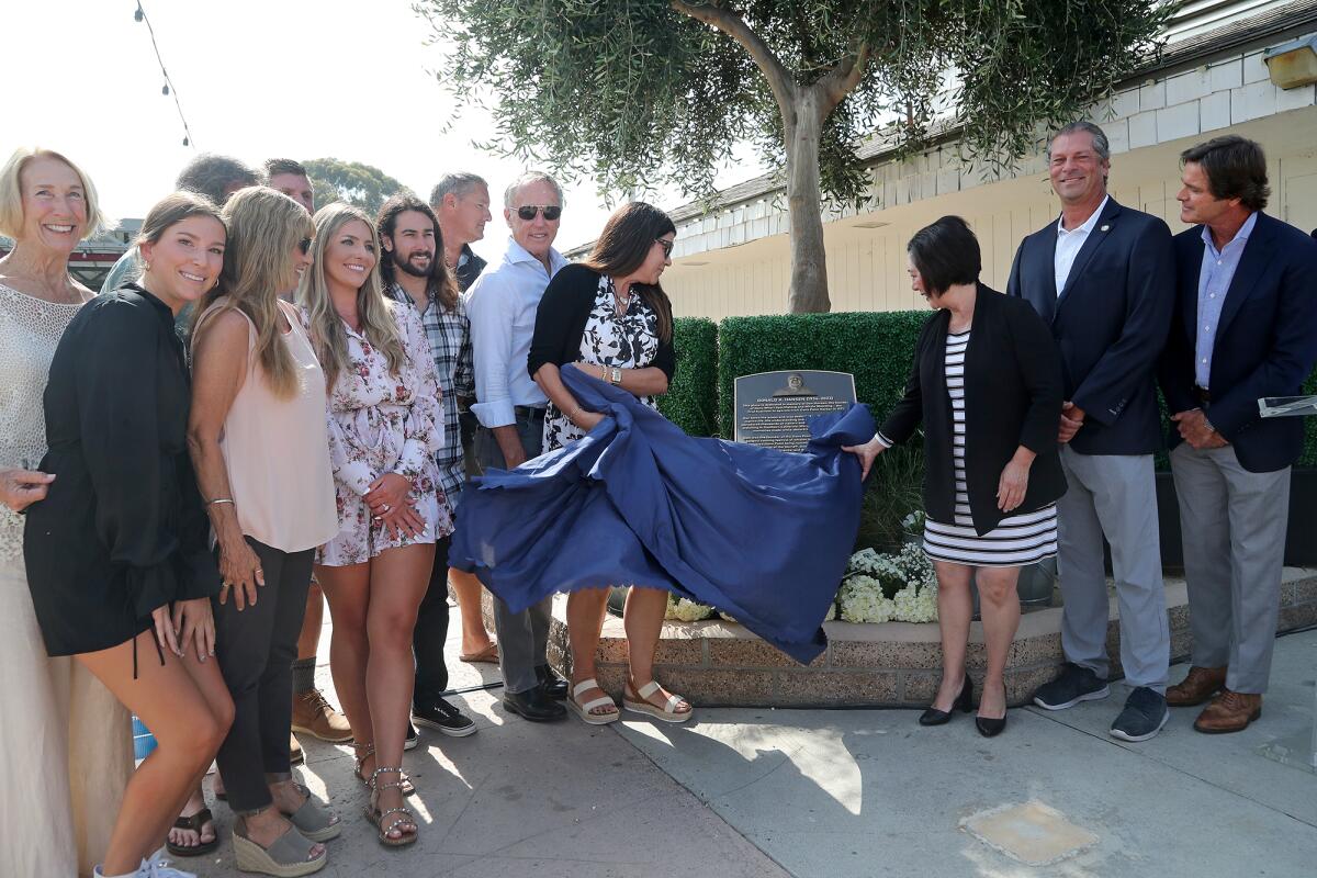 Donna Kalez, left, and O.C. Supervisor Lisa Bartlett, right, pull the covering off as they unveil the Hansen Plaza plaque.  