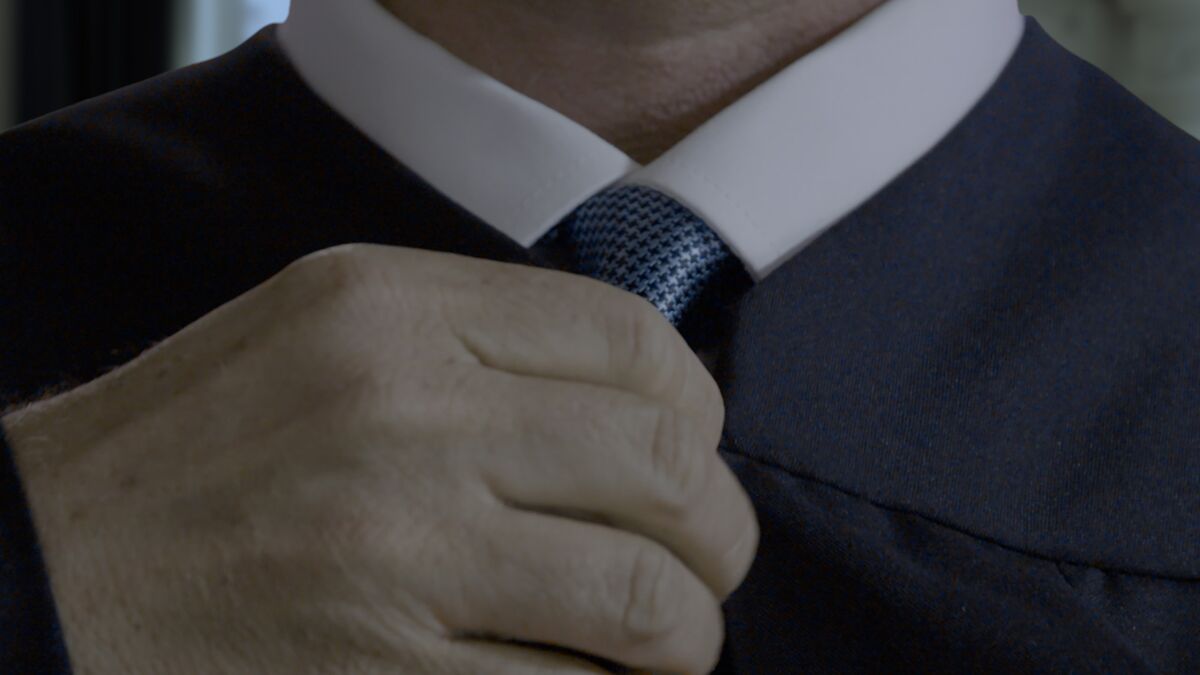 A close-up of a man adjusting his tie