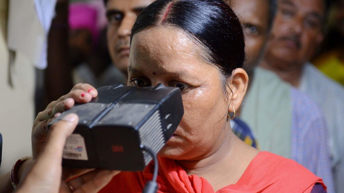 An Indian woman looks through an optical biometric reader to register for her Aadhaar card.