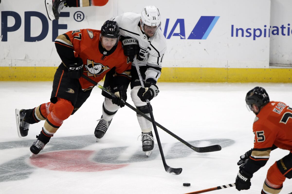 Kings center Anze Kopitar, center, competes for the puck with Ducks defenseman Hampus Lindholm.
