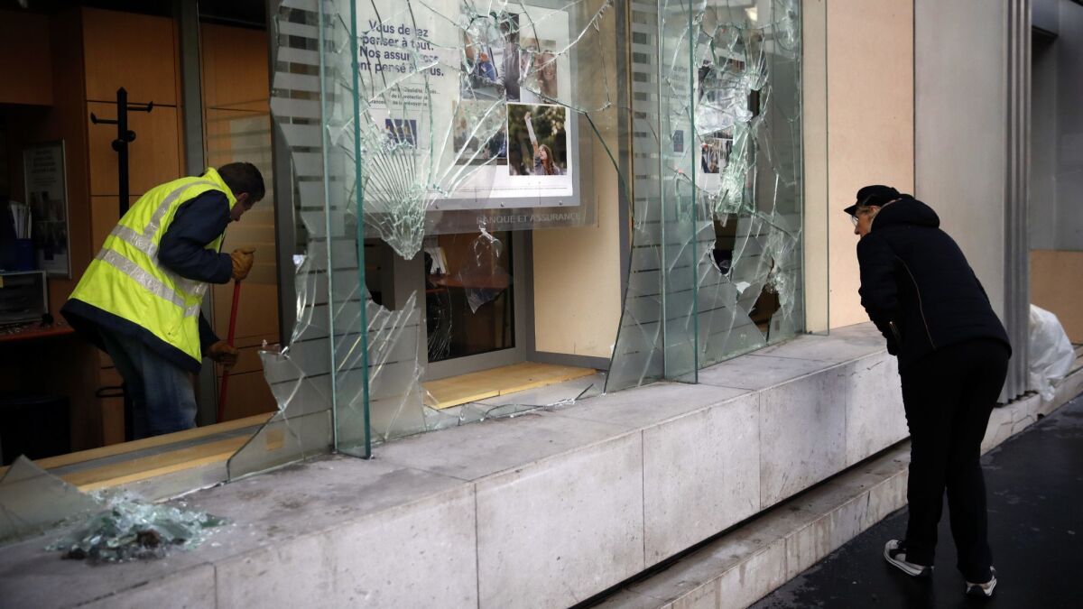 After another weekend of demonstrations, a worker clears debris from a Paris bank on Dec. 9.