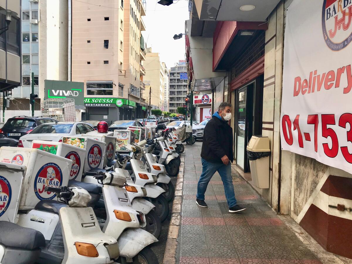 An employee walks into Barbar restaurant in Beirut, past its fleet of delivery scooters.