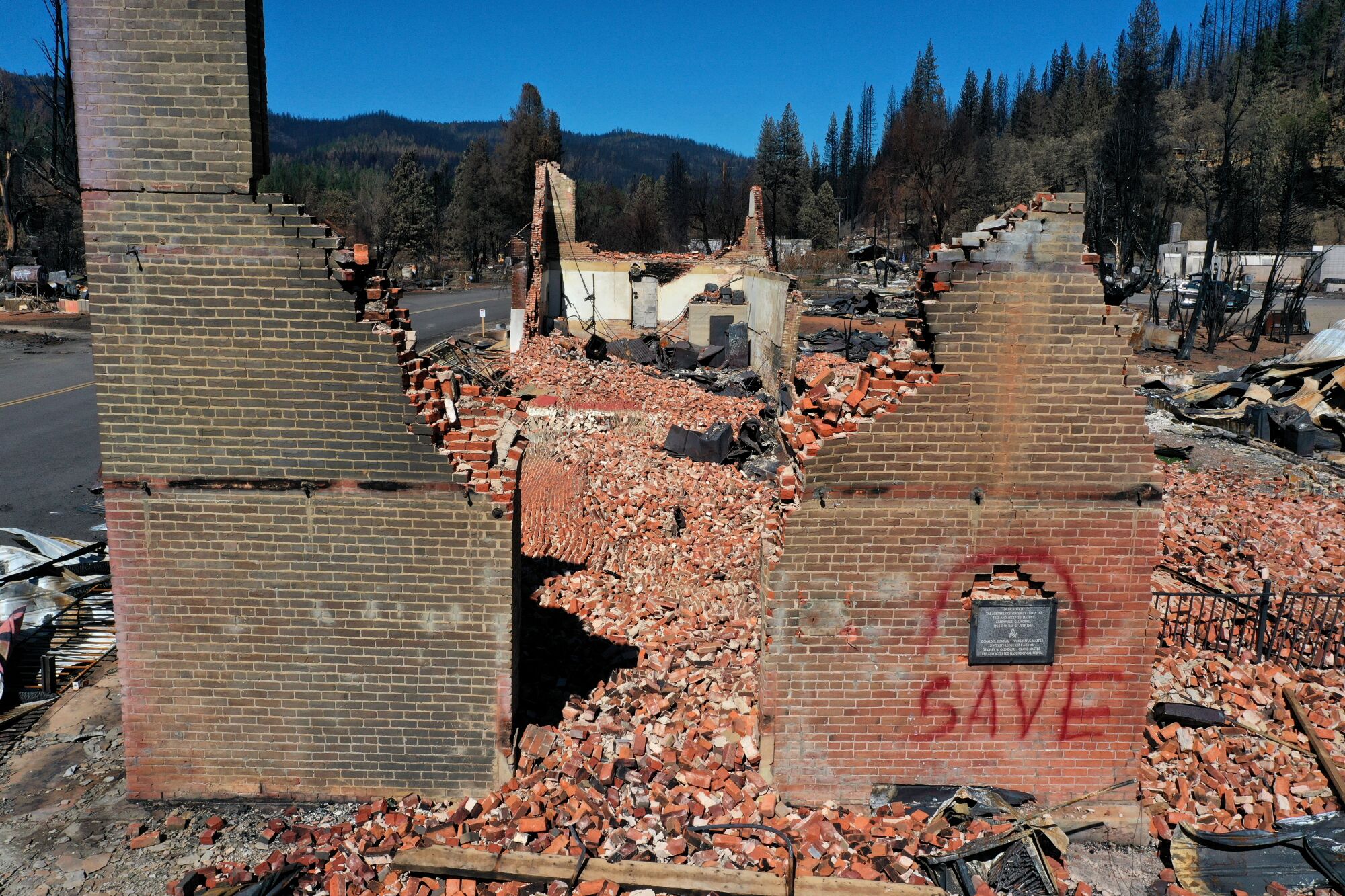 Two brick walls stand amid rubble, one with the word "save" painted on it 