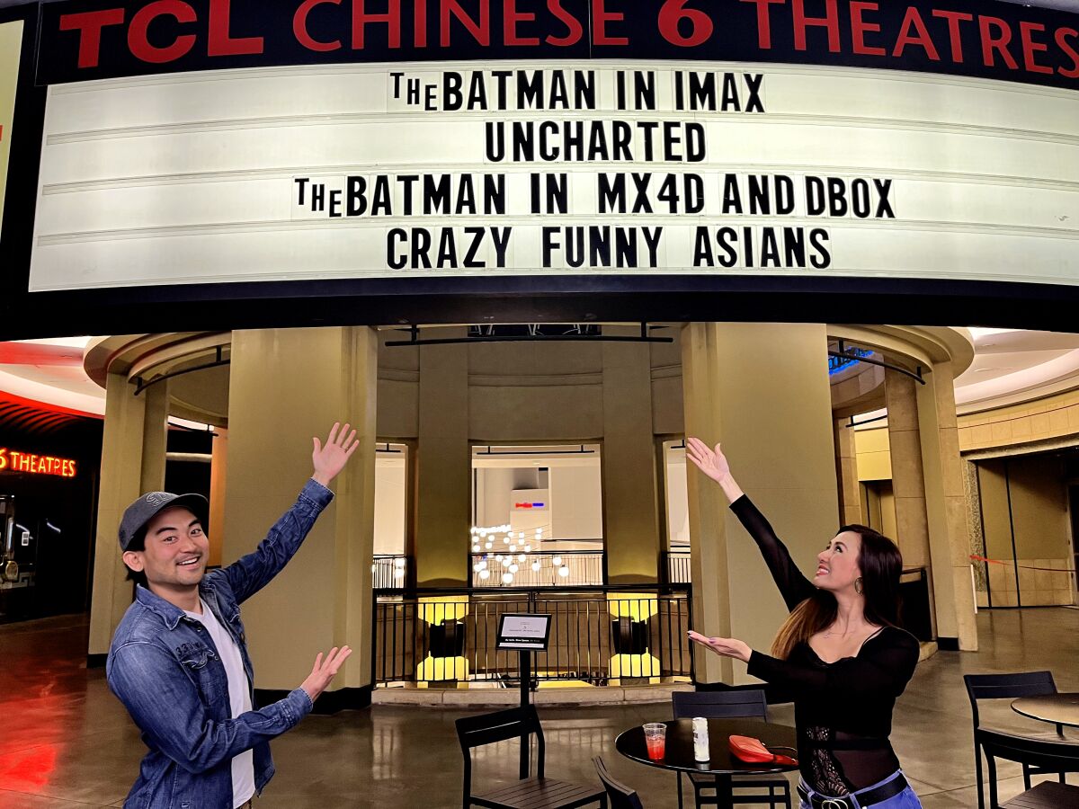 Two people point at a movie theater marquee. 