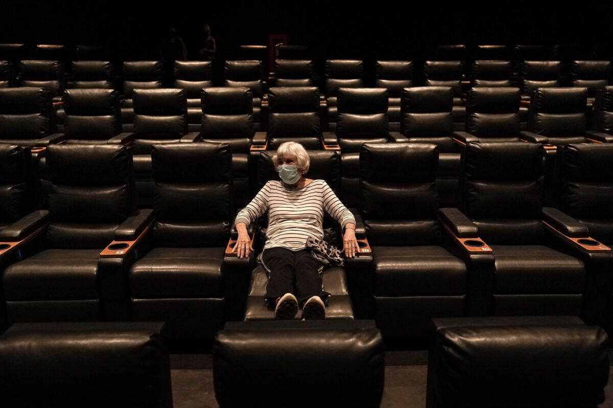 Karen Speros, 82, waits for a movie to start at a Regal movie theater in Irvine, Calif., Tuesday, Sept. 8, 2020. California Gov. Gavin Newsom relaxed coronavirus restrictions in five more counties on Tuesday, clearing the way for restaurants, movie theaters, gyms, and churches to resume indoor activities with fewer people and other modifications. (AP Photo/Jae C. Hong)