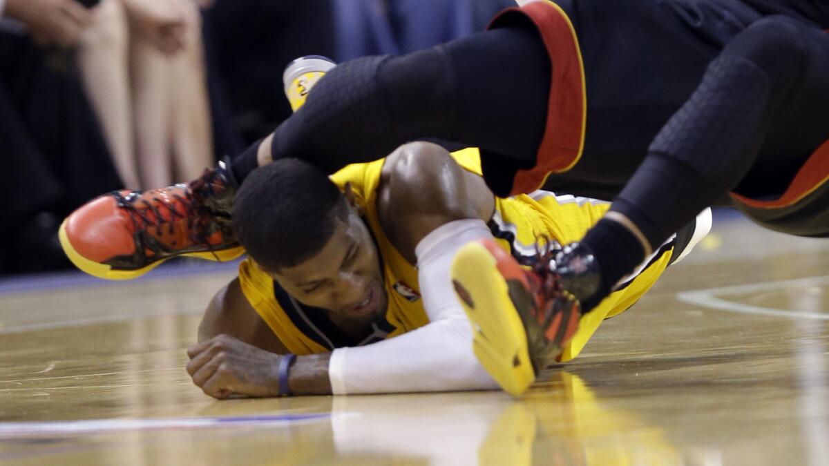 Indiana Pacers forward Paul George lies on the floor as the knee of Miami Heat guard Dwyane Wade makes contact with his head during Game 2 of the Eastern Conference finals Tuesday. George suffered a concussion on the play.