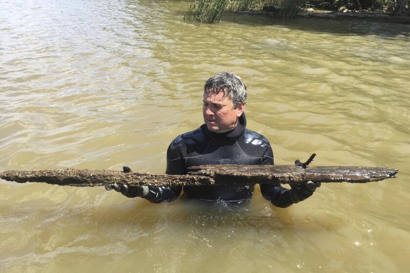 Ben Raines holds pieces of the Clotilda, subject of his new book, "The Last Slave Ship," in the Mobile River, 2019.