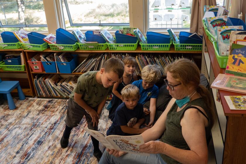 KNEELAND, CA - AUGUST 31: Teacher's aide Cheryl Furman reads to Jace Johnson, left; Evie Hippen; Ryden Sizemore and Edward Rich in the transitional kindergarten to second grade class at Kneeland School. It's one of the smallest public schools in California and has been around since 1880. It's a California "necessary small school," that had just 12 kids enrolled in grades K-8 a few years ago. But it exploded during the pandemic to 33 kids -- and went from two teachers to a "huge staff" of eight, per the superintendent -- because people wanted in-person schooling and ended up staying. Photographed on Wednesday, Aug. 31, 2022 in Kneeland, CA. (Myung J. Chun / Los Angeles Times)