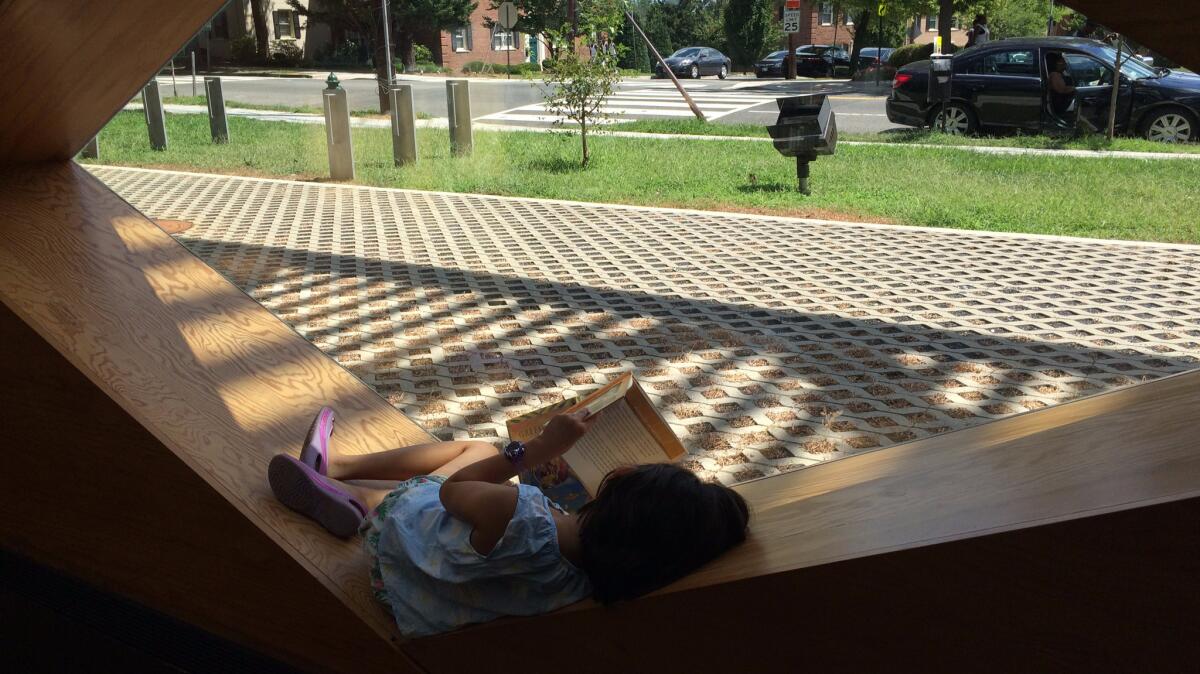 A child catches up with her reading in the window boxes created by Adjaye's geometric screen.