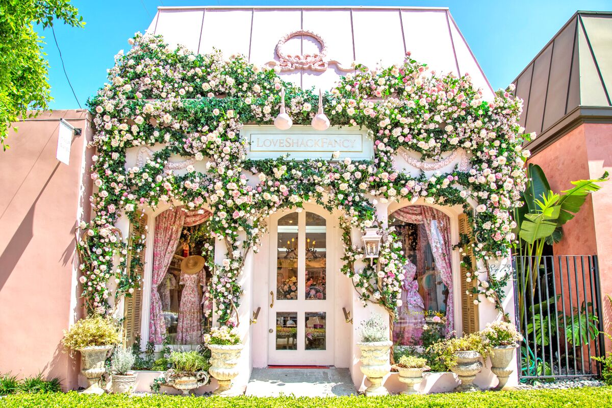 The entrance of LoveShackFancy's Melrose Place flagship, a rose-covered-cottage.