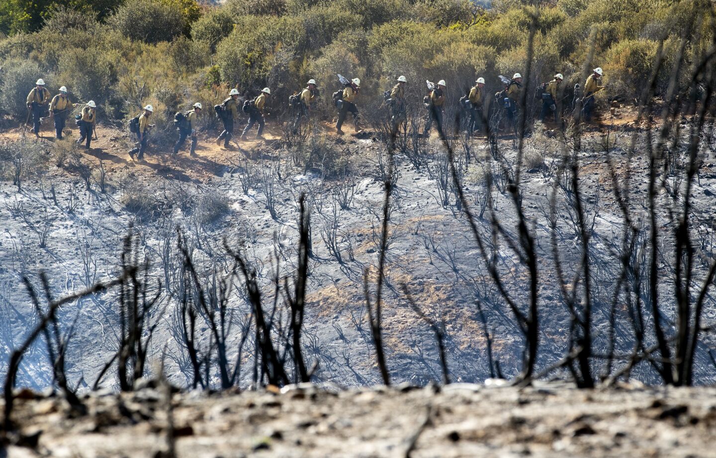Wildland firefighters work a line to douse hot spots along Avenida Miravilla in Cherry Valley, Calif.