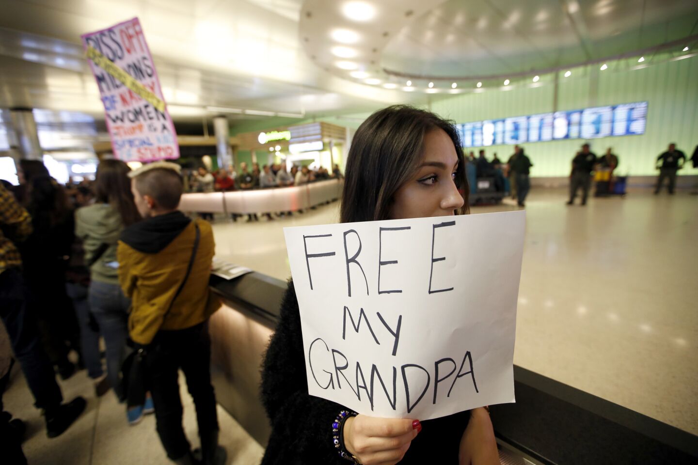 Kamryn Taghizadeh, 18, holds up a sign Saturday night as she waits for grandfather Reza Taghizadeh, 78, a minimalist painter who was detained as he arrived at Tom Bradley International Terminal from Iran. The artist and green-card holder was later released.