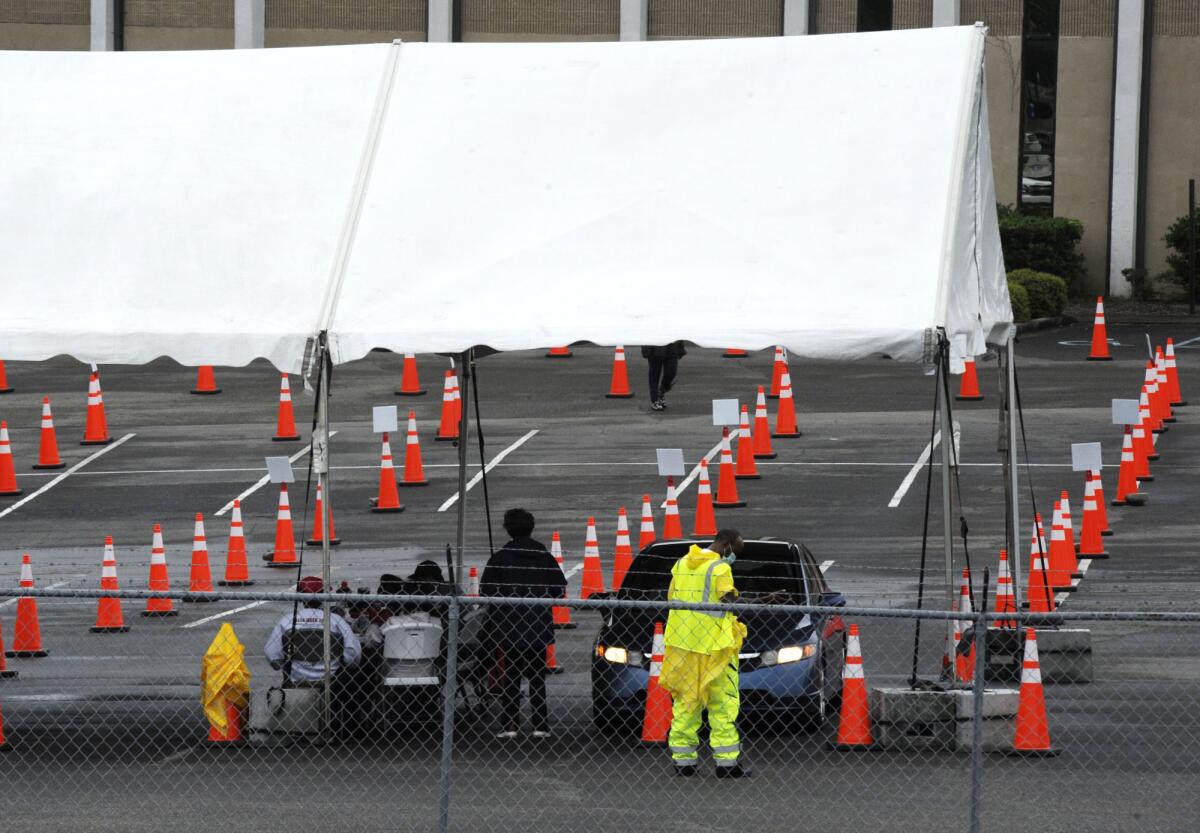 Rows of traffic cones and a canopy on a parking lot.