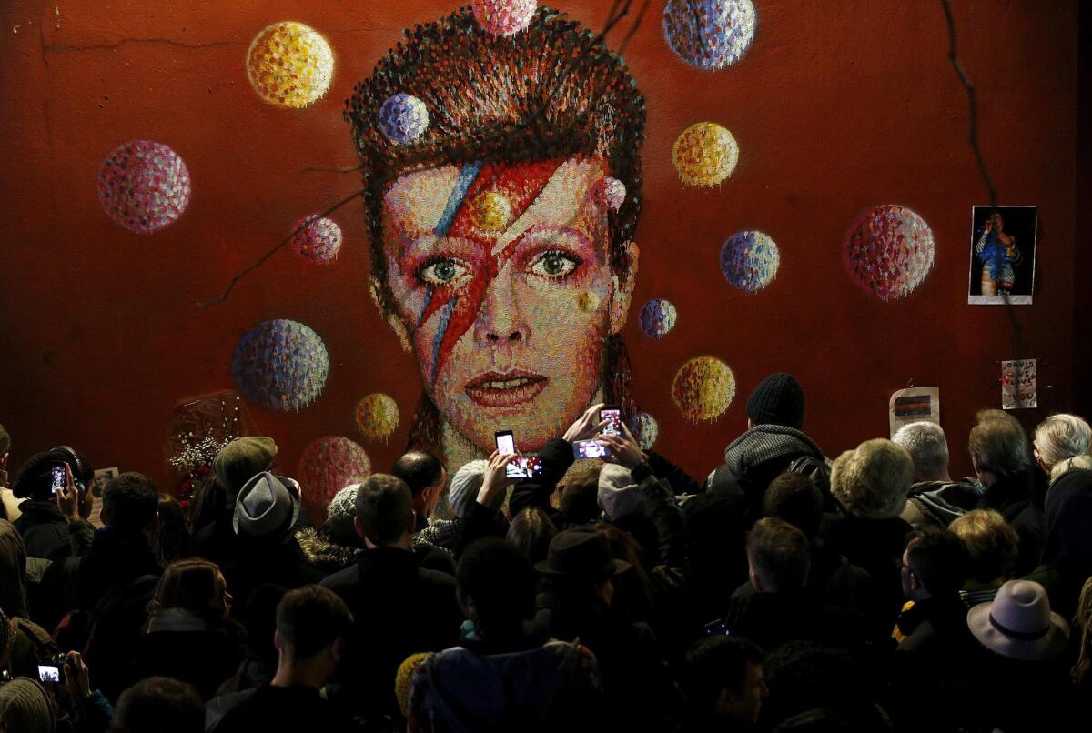 Los admiradores de David Bowie se reúnen ante un mural de Londres que lo refleja en su etapa de Ziggy Stardusts luego de conocer la noticia de su muerte a los 69 años de edad.