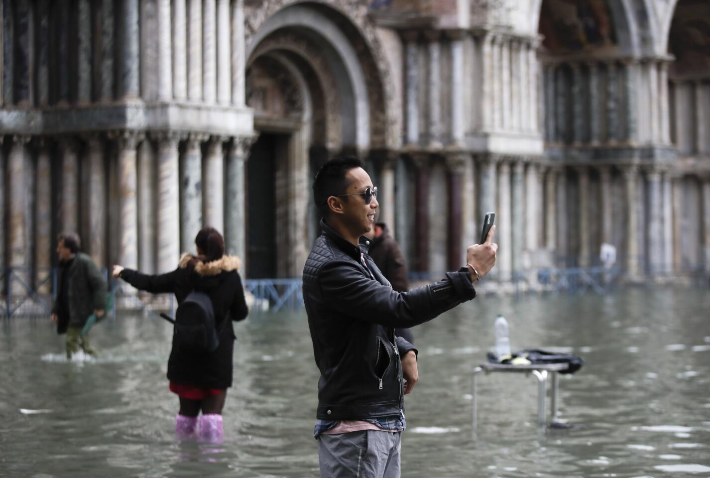 Tourists take pictures in a flooded St. Mark's Square in Venice.