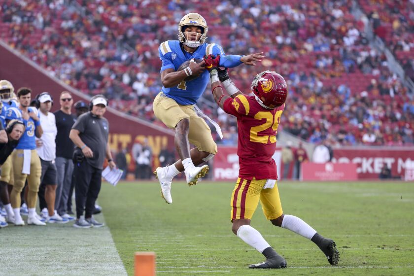 UCLA quarterback Dorian Thompson-Robinson, left, leaps in attempt to get past USC safety Xavion Alford
