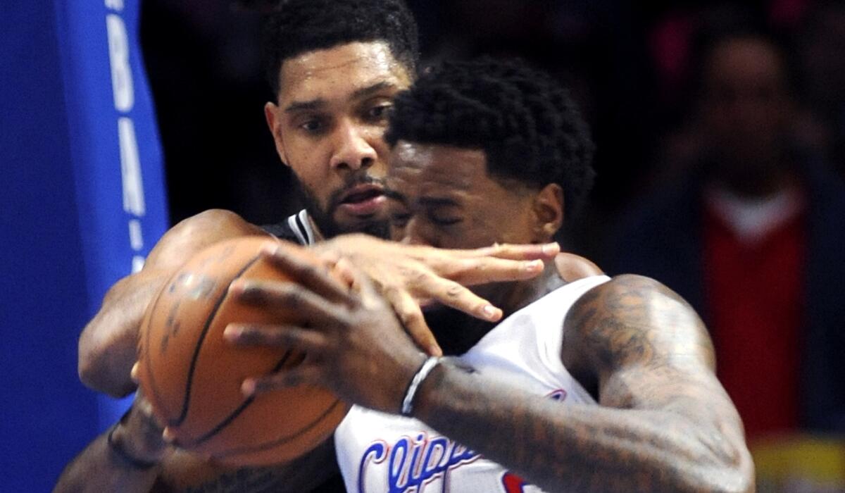 Clippers center DeAndre Jordan is fouled by Spurs forward Tim Duncan while trying to drive to the basket in the first half.