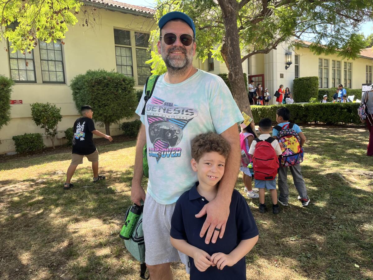 A man stands with his 7-year-old son outside of Aldama Elementary School.