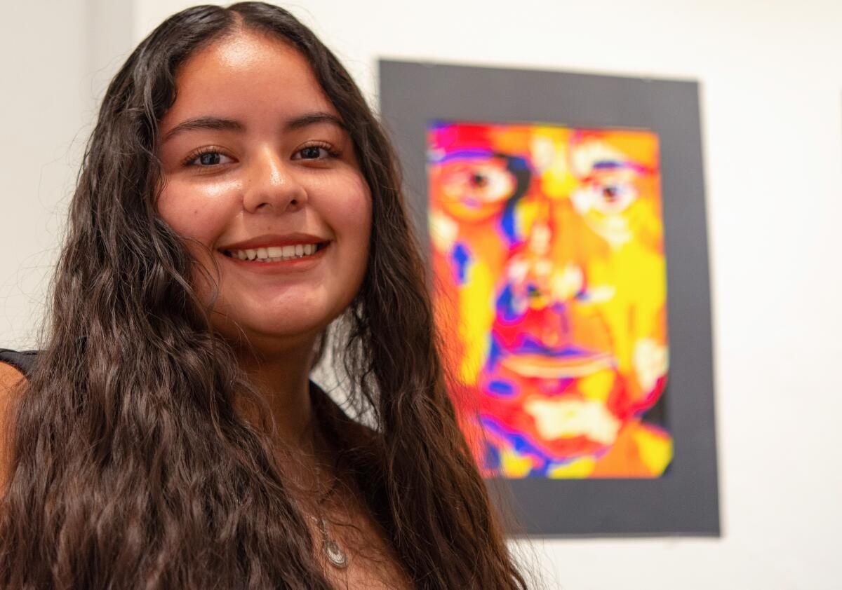 Santiago High junior Aracely Santana stands next to her drawing, "Mettle," at the "Color It Orange" exhibit.