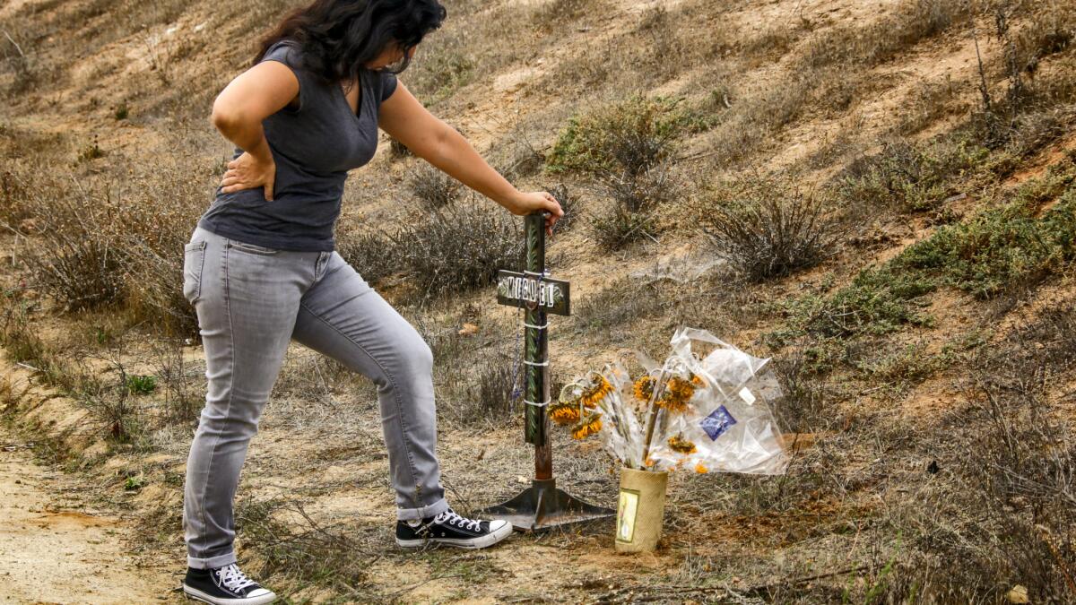 Michelle Glenn offers prayers at a makeshift memorial in front of the home where her cousin, Miguel Ferreyra, and four other adults died in a suspicious fire that gutted a care facility in Temecula.