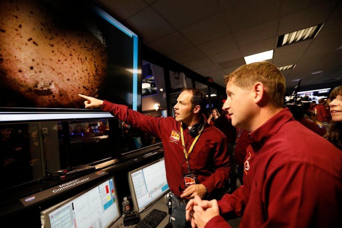 At JPL, flight team engineers Devin Kipp, left, and Daniel Litton look at the first image beamed back after the successful landing of the NASA InSight spacecraft.