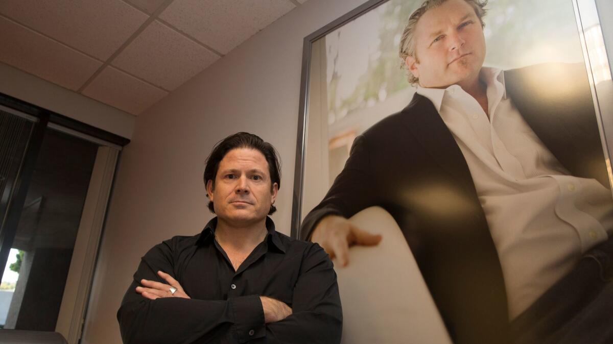 Breitbart News CEO Larry Solov, with a portrait of late founder Andrew Breitbart, at the company's offices in Los Angeles.