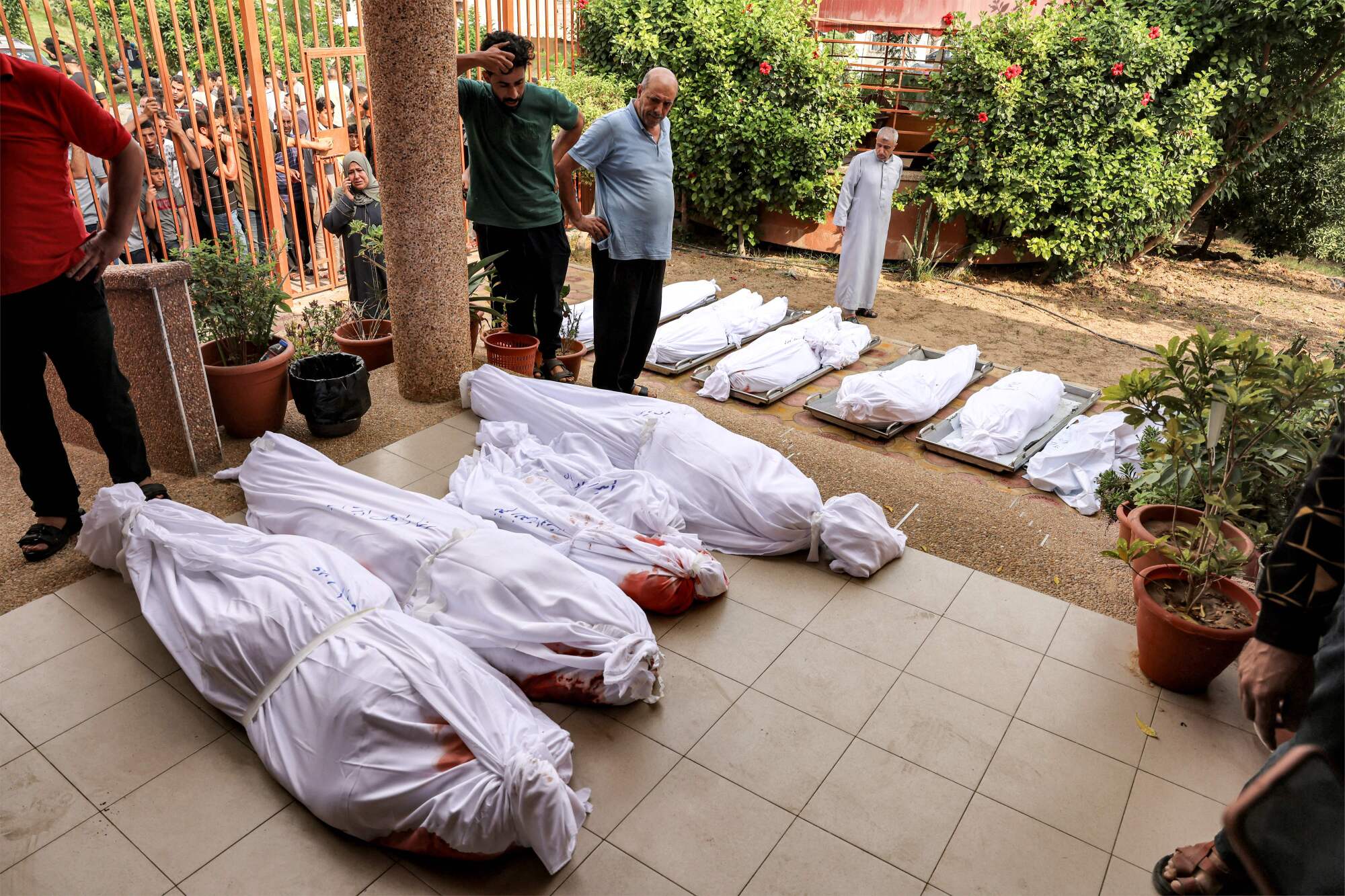People gather at a morgue by the wrapped bodies of Palestinians killed in an Israeli airstrike.