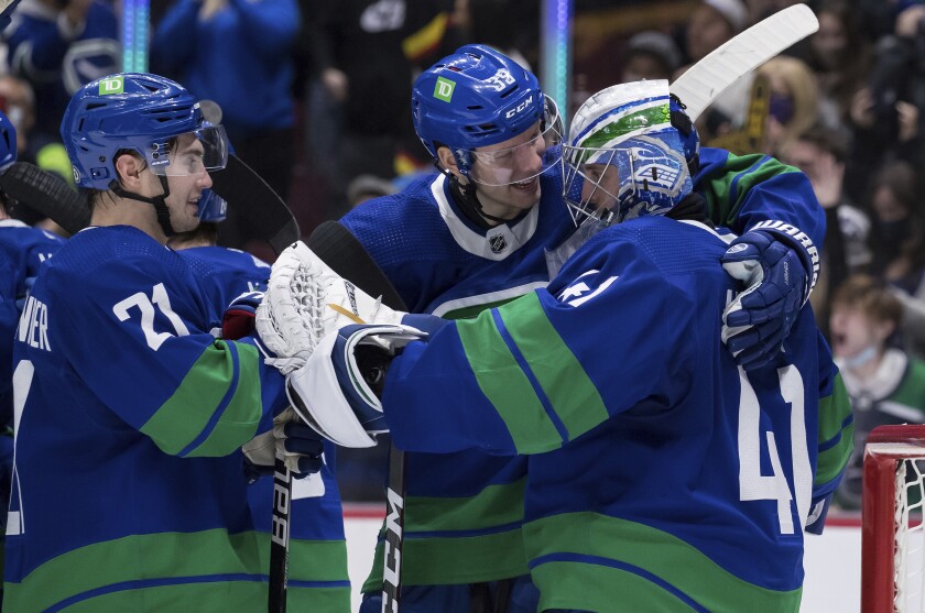 Vancouver Canucks' Nils Hoglander, of Sweden, from left to right, Alex Chiasson and goalie Jaroslav Halak, of Slovakia, celebrate after Vancouver defeated the Columbus Blue Jackets 4-3 after an NHL hockey game Tuesday, Dec. 14, 2021 in Vancouver, British Columbia. (Darryl Dyck/The Canadian Press via AP)