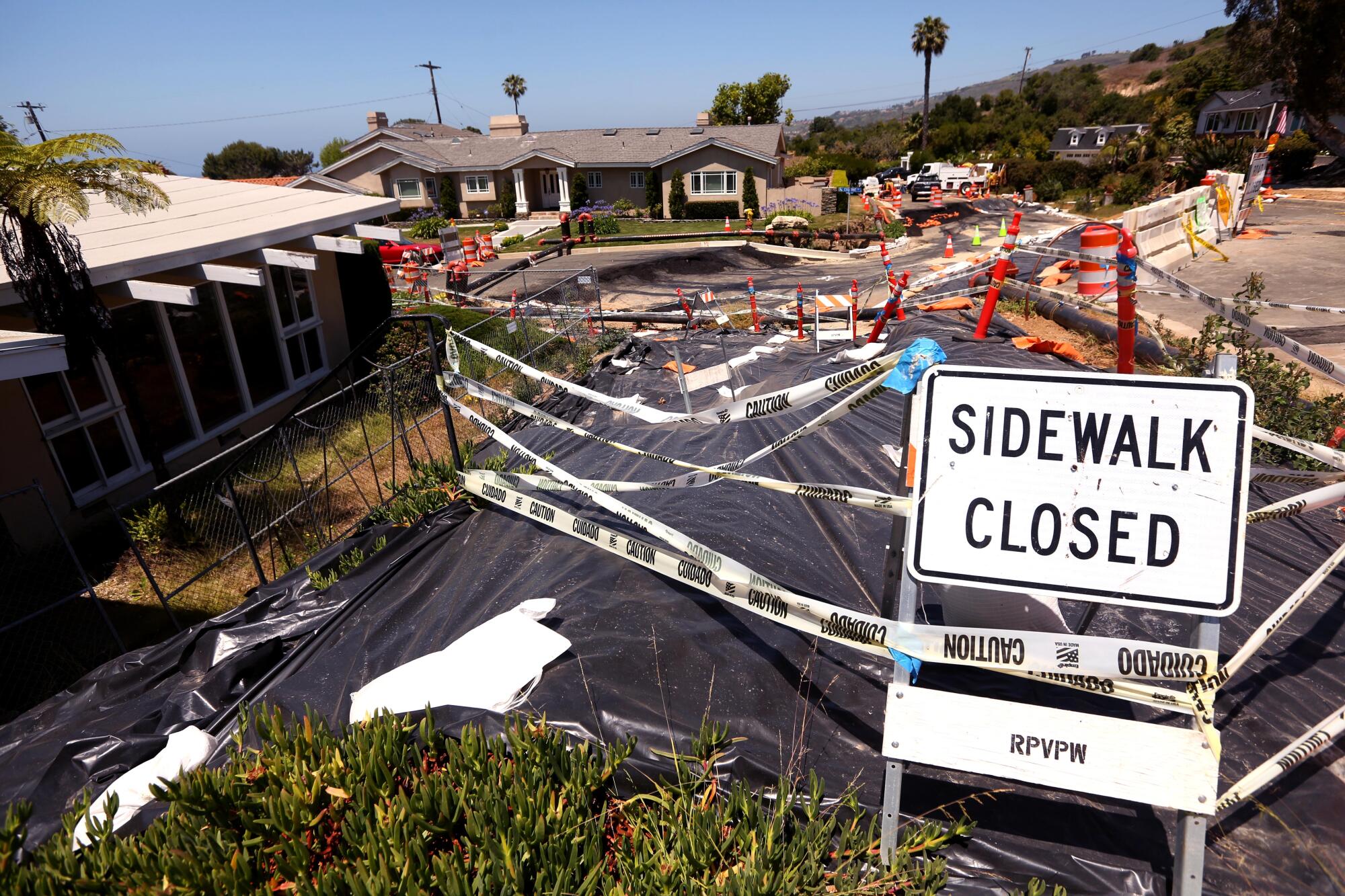 Plastic sheeting covers the ground near a sign reading "sidewalk closed."