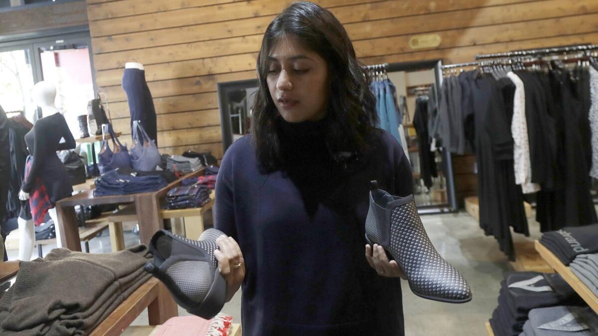 At a Betabrand store in San Francisco, Ayesha Tellis holds up shoes she designed on her computer.