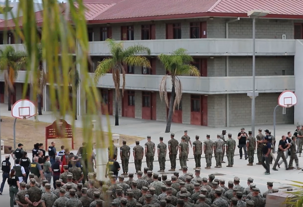 In this video screenshot, NCIS agents and other law enforcement approach the 16 Marines in front of the battalion formation at Camp Pendleton.